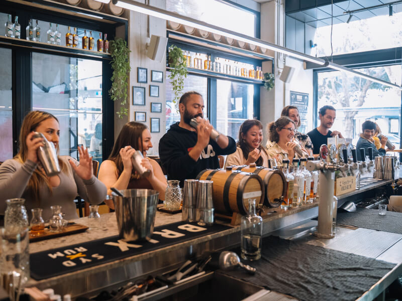 A group of people shaking cocktails at a cocktail class.